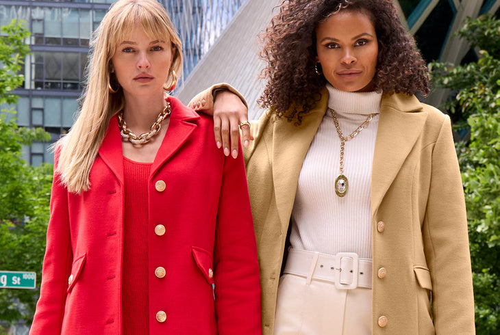 Two stylish women wearing tailored outerwear from Boston Proper, featuring a bold red coat and a sophisticated camel coat paired with chic layering, designed by Boston Proper.