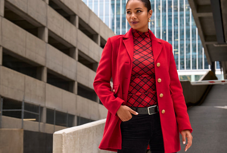 Confident woman wearing a red tailored coat with gold buttons and a plaid top, styled for effortless layering in Boston Proper fashion.